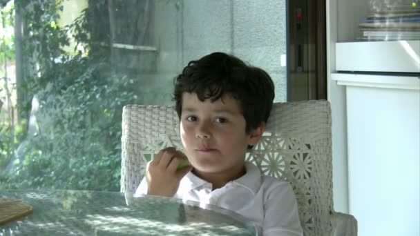 Child eating green apple and smiling to camera — Stock Video