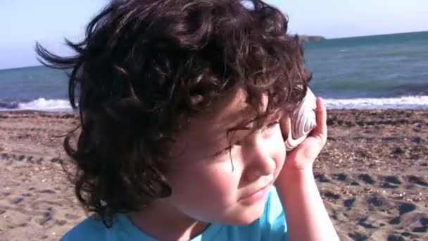 Niño pequeño escuchando a la concha marina — Vídeos de Stock