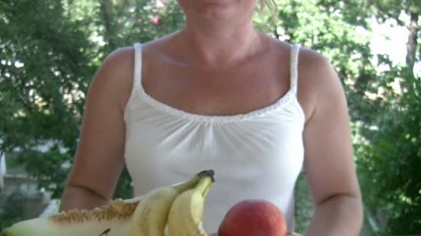 Женщина держит тарелку с фруктами — стоковое видео