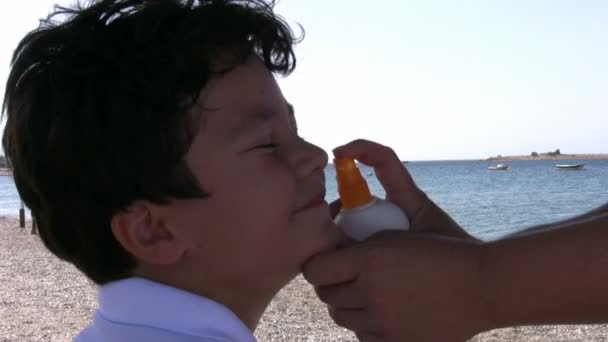 Mãe aplicando loção bronzeada ao filho — Vídeo de Stock