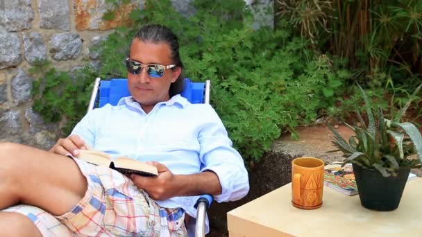 Mann liest ein Buch im Garten — Stockvideo