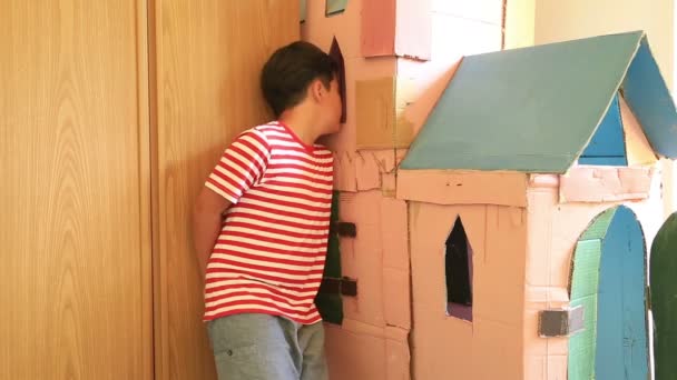 Portret van een jongen in de buurt van het huis van karton — Stockvideo