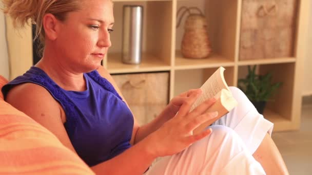 Vrouw zittend op de bank en leesboek — Stockvideo