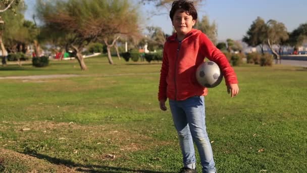 Portrait d'un enfant heureux avec une balle souriant à une caméra — Video