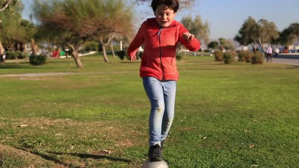 Мальчик пинает мяч в траве на открытом воздухе — стоковое видео