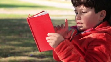 9 yaşında bir çocuk üzerinde çim okuma oturan bir çocuk kitabı