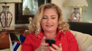 Sarışın kadın kanepede Smartphone kullanarak