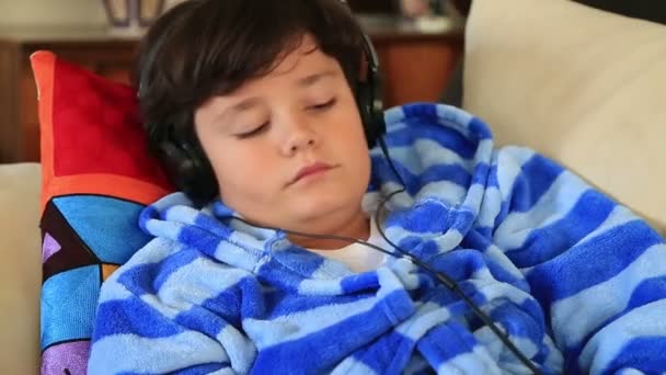 Young boy listening to music on a couch — Stock Video