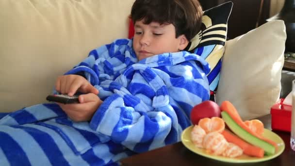 Bambino di 9 anni che guarda la tv sdraiato sul divano di casa — Video Stock