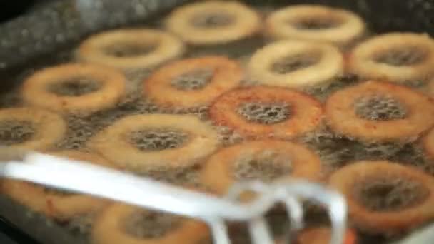 Arany ropogós hagymakarikák egy serpenyőben sütés — Stock videók