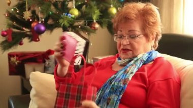 Olgun kadınla sürpriz hediye kutusu, Noel ağacı yakınındaki kanepede oturan portresi