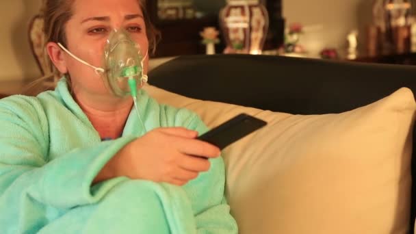 Женщина в кислородной маске смотрит телевизор — стоковое видео