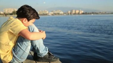 Mutsuz çocuk ahşap bir iskele üzerinde