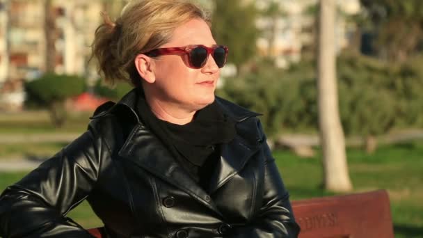 Портрет женщины, сидящей на скамейке в парке 5.mov — стоковое видео