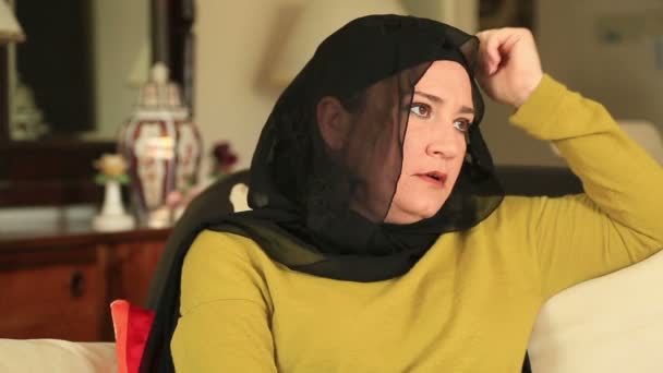 Грустная мусульманка сидит на диване — стоковое видео