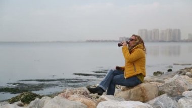 Deniz tarafında oturan ve kahve içme kadın