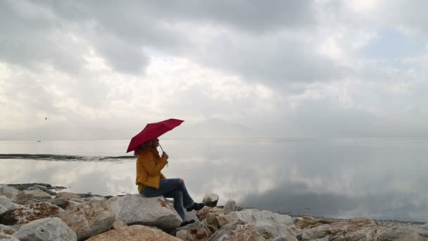 女人用伞坐在海的那边 — 图库视频影像