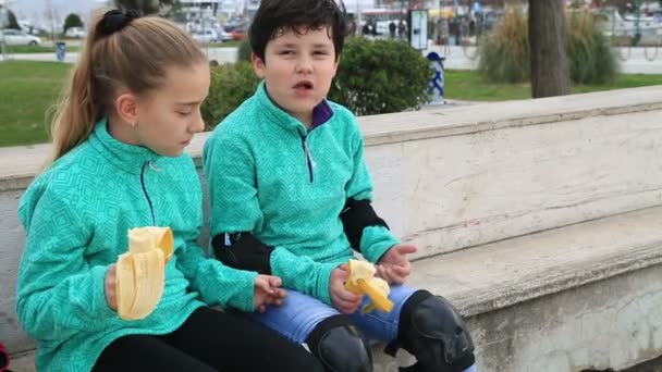 Młodych łyżwiarzy jedzenie bananów — Wideo stockowe