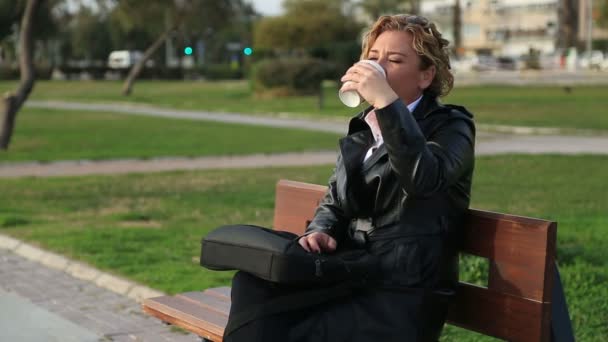 Mujer de negocios en descanso tomando café en un parque — Vídeo de stock