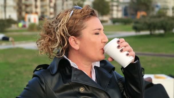 Zakenvrouw op lunch break in stadspark koffie drinken — Stockvideo