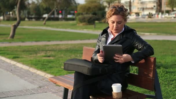 Biznes kobieta za pomocą tabletu na przerwę obiadową w parku miejskim. — Wideo stockowe