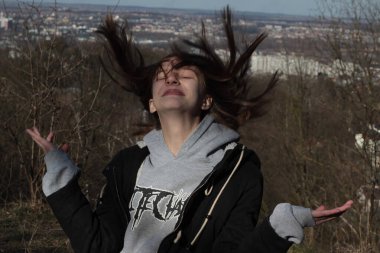 Baharın başında dağda genç bir kız, şehrin arka planında dalgalı saçları olan yüzü poz veriyor.