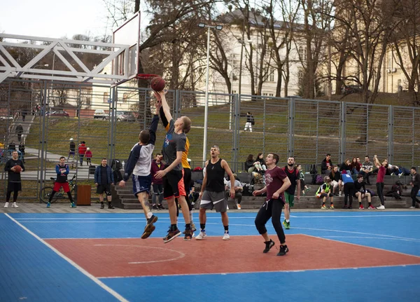 Erkekler parktaki özel bir spor alanında basketbol oynarlar.