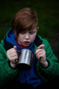 Kızıl saçlı adam doğada yemek yiyor.