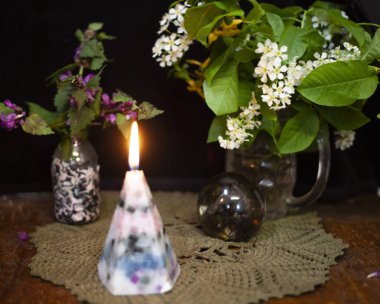 Durgun bir hayat yanan bir mum, beyaz çiçekli bir vazo, mor koşullar ve cam bir top