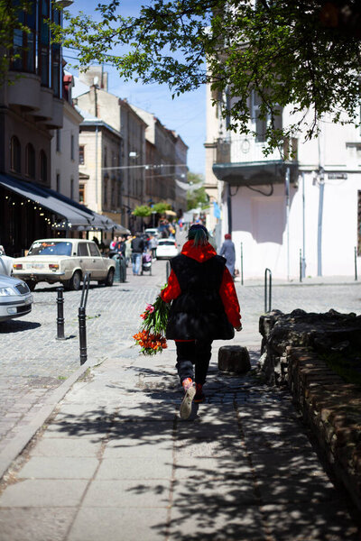 The girl carries a bouquet of orange lilies on the street of the old town