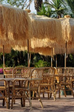 Tablolar ve restoranda saman şemsiye ile hasır sandalyeleri 