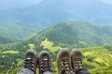 Hiking boots of traveler sitting on high mountain top clipart
