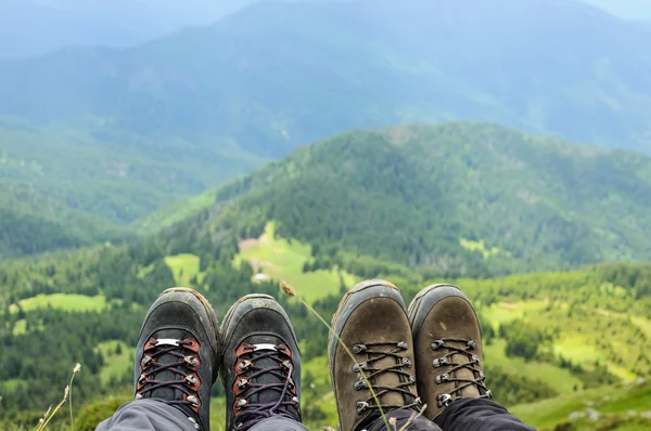 Hiking boots of traveler sitting on high mountain top — Stock Photo, Image