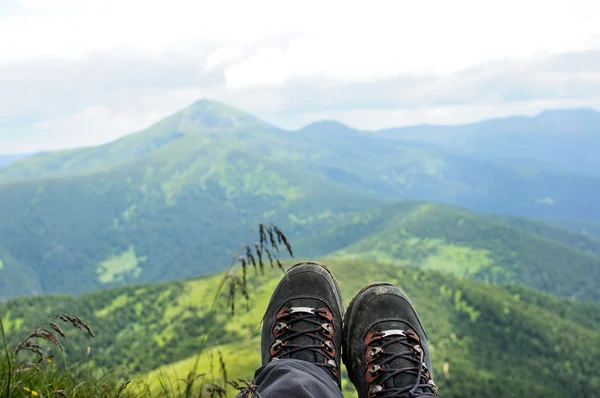 Hiking boots of traveler sitting on high mountain top — Stock Photo, Image