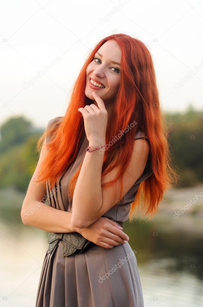 Outdoors portrait of beautiful young woman with red hair