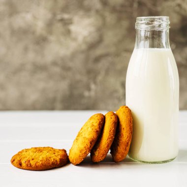 Tahta masada bir şişe süt ve portakallı kurabiye.