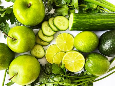 Taze sebzeler ve meyveler, yeşiller, limon, salatalık, elmalar beyaz bir masada.