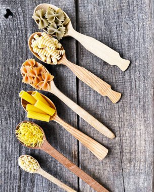 Masadaki tahta kaşıklarda farklı türde makarna.