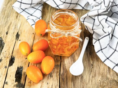 Tahta bir masada kahvaltı için portakal reçeli ve kumkat.