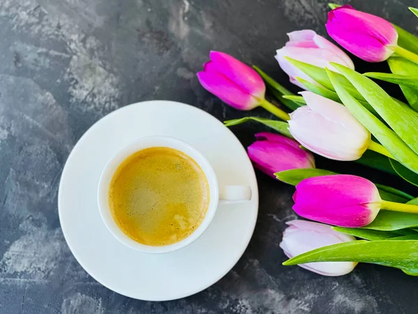 bouquet of colored tulips and coffee in a white cup