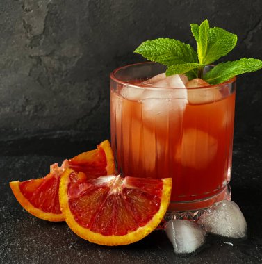 Bir bardak Sicilya portakal suyu, buzlu ve naneli siyah beton.