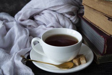 Eski kitaplar, çay, karanlık bir masanın üstünde.