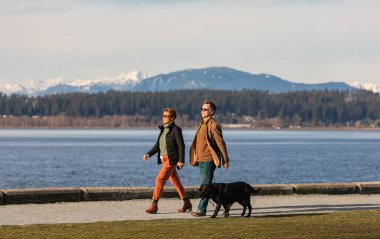 Erkekler ve kadınlar köpeklerini deniz kıyısındaki bir spor salonuna götürürler. White Rock, BC, Kanada-8 Mart 2021. Seçici odak, sokak manzarası, seyahat fotoğrafı.