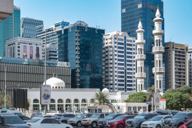 Abu Dabi şehir merkezi, UAE silueti ve modern binalar, konut evleri ve oteller, otoparkında arabaları olan cami. Konut kompleksindeki daireler. Seyahat fotoğrafı: 19 Nisan 2025