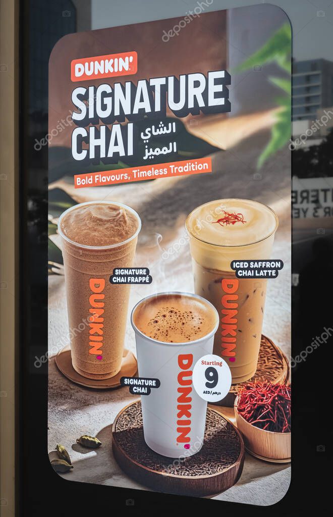 Logo sign of Dunkin' Donuts on the store facade. A close-up of an advertising Dunkin' sign on a storefront in Abu Dhabi UAE, hot chai cups on colorful background-April 19,2025-Editorial