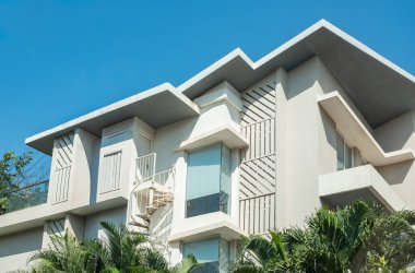 Beyaz cepheli, balkonlu ve teraslı, mavi gökyüzü arka planlı modern lüks ev. Yeni modern mimari. Konut geliştirme. Minimalist tasarımı olan lüks ve modern bir villa