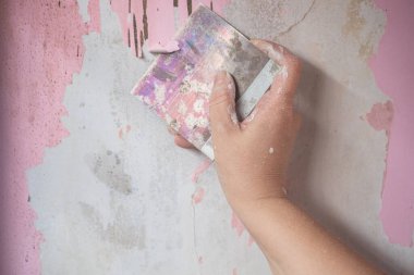 Duvardaki eski boyayı çıkarmak için duvar boyasını kazıyıcı ile kazımış. Duvar Tamiri Süreci. Beton duvardaki eski boyayı çıkarmak için el boyası çıkarıcı kullanıyor. Ev rengini boya ve yenilemeyi hazırlayın.