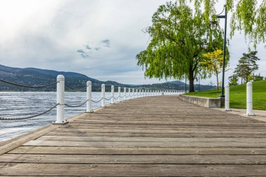 Doğal bir parkta güzel bir ahşap patika boyunca yürüyorum. Şehir parkında nehir kenarındaki modern tahta kaldırım. Eğlence alanı olarak. Doğa, çevre, eko-turizm, tatiller, hafta sonu