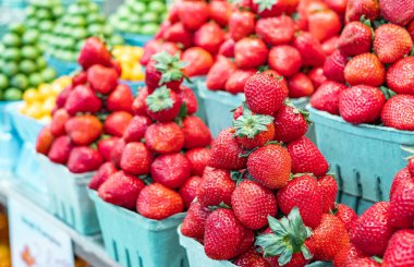 Organik meyve ve sebzelerle dolu bir tezgah. Yerel bir markette satılığa çıkarılan taze olgun çilekler. Kırmızı çilekler geri dönüşümlü kaplarda paketlenir. Çevre dostu karton kutular