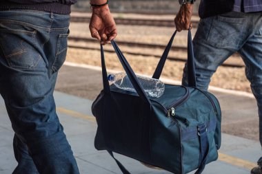 Seyahat çantalı insanlar istasyonda yürüyor. İki tanınmayan adamın tren istasyonunda ağır bir çanta taşıdığını gördüm..